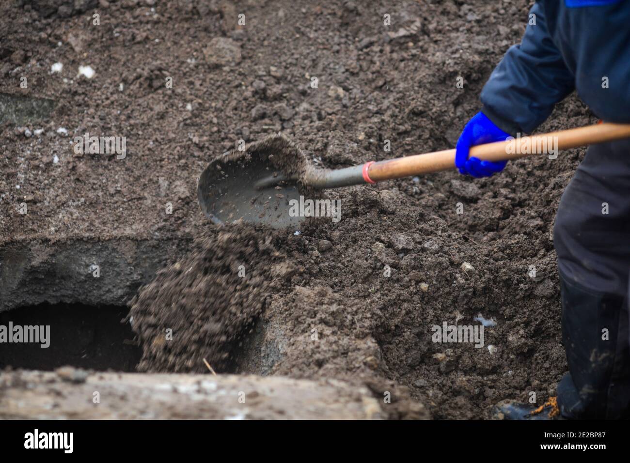 Details of a gravedigger covering a tomb with dirt with a shovel