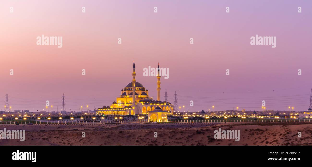 New Sharjah Mosque, the largest mosque in the Emirate of Sharjah, the United Arab Emirates, panorama with pink sky sunset background. Stock Photo