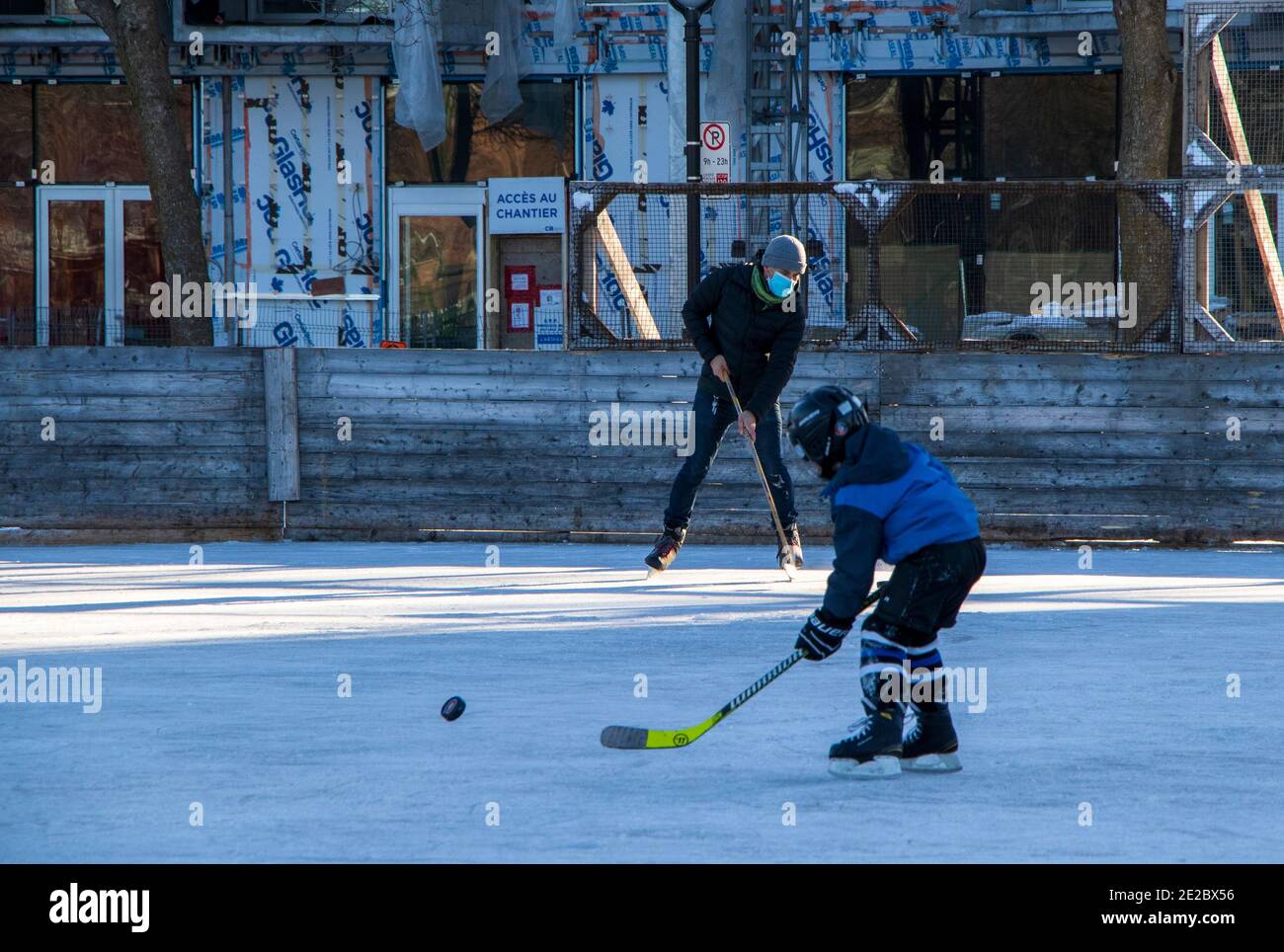 January 9, 2021 - Montréal, Qc, Canada: Man wearing a face mask while playing hockey with a child during COVID Coronavirus Pandemic, Rosemont borough Stock Photo