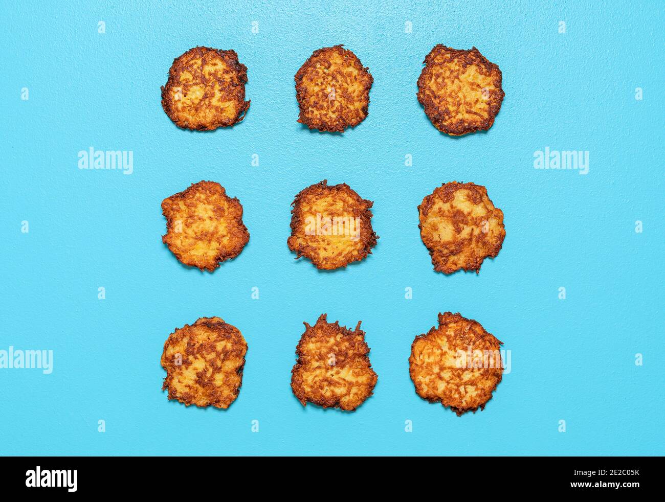 Homemade potato pancakes aligned symmetrically in a square on a blue background. Fried potato pancakes above view. Stock Photo