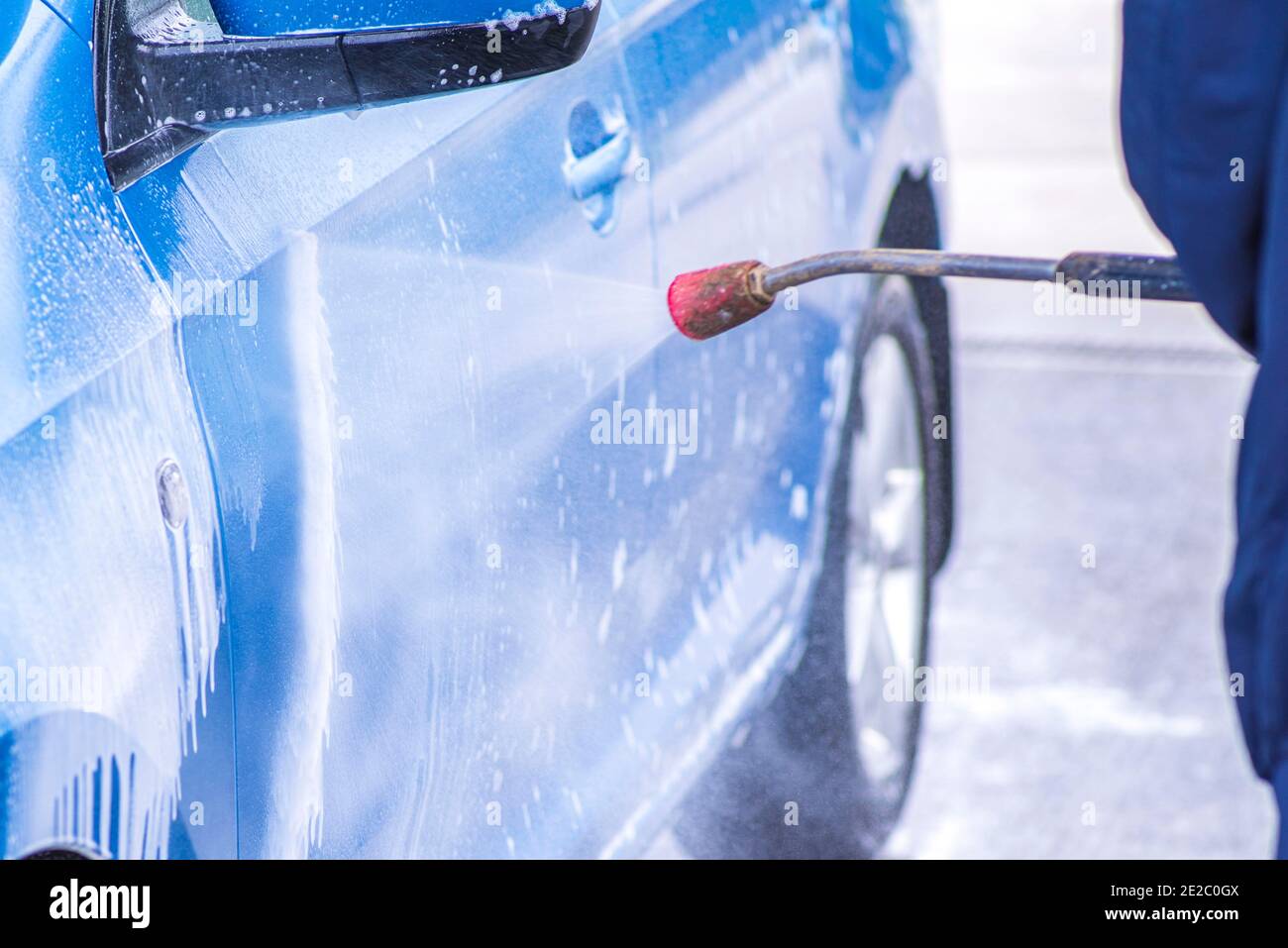 A man washes a car on his own. Car wash selfservice. Cheap car wash