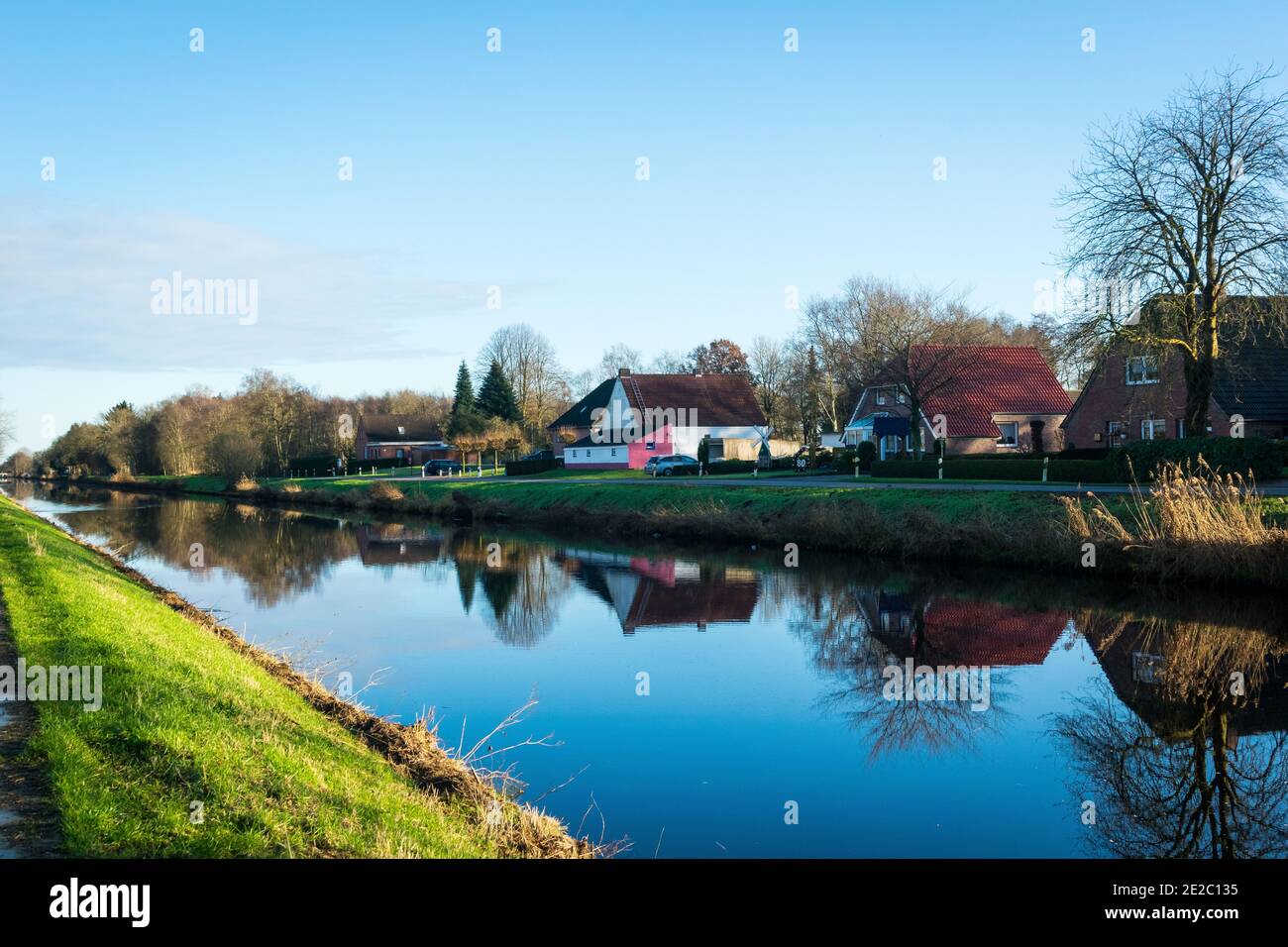 Landscape of houses along the path near Emsj-Jade Canal in East Friesland Stock Photo