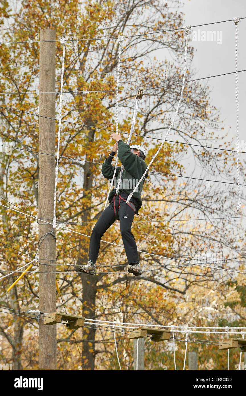 High ropes/challenge course. Participant crossing guide wires Stock