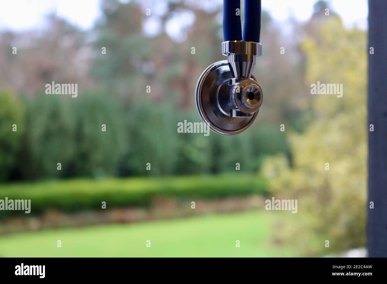Stethoscope hanging in window space with blurred garden in background Stock Photo