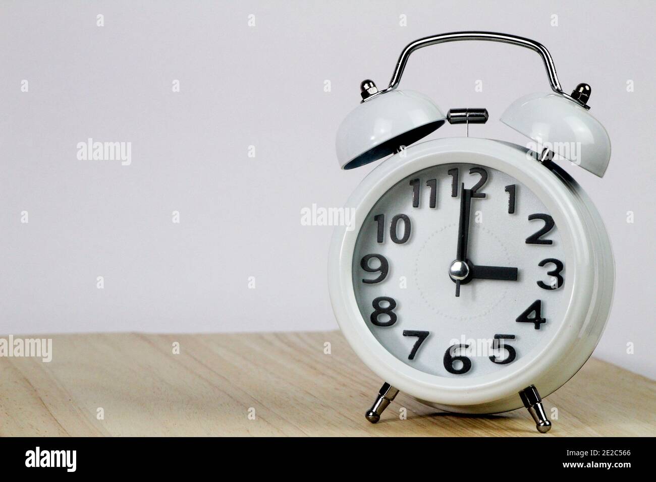 Old mechanical alarm clock on wooden table and white background showing