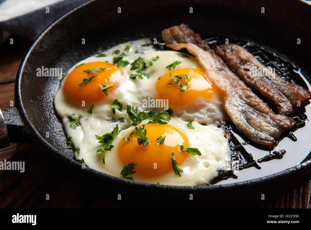 Scrambled eggs and bacon in a small pan on the kitchen table Stock Photo