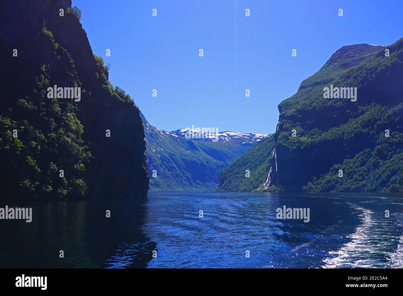 Touring the Norwegian Geirangerfjord by ferry on a clear summer day. The Seven Sisters waterfall can be seen in the background. Stock Photo