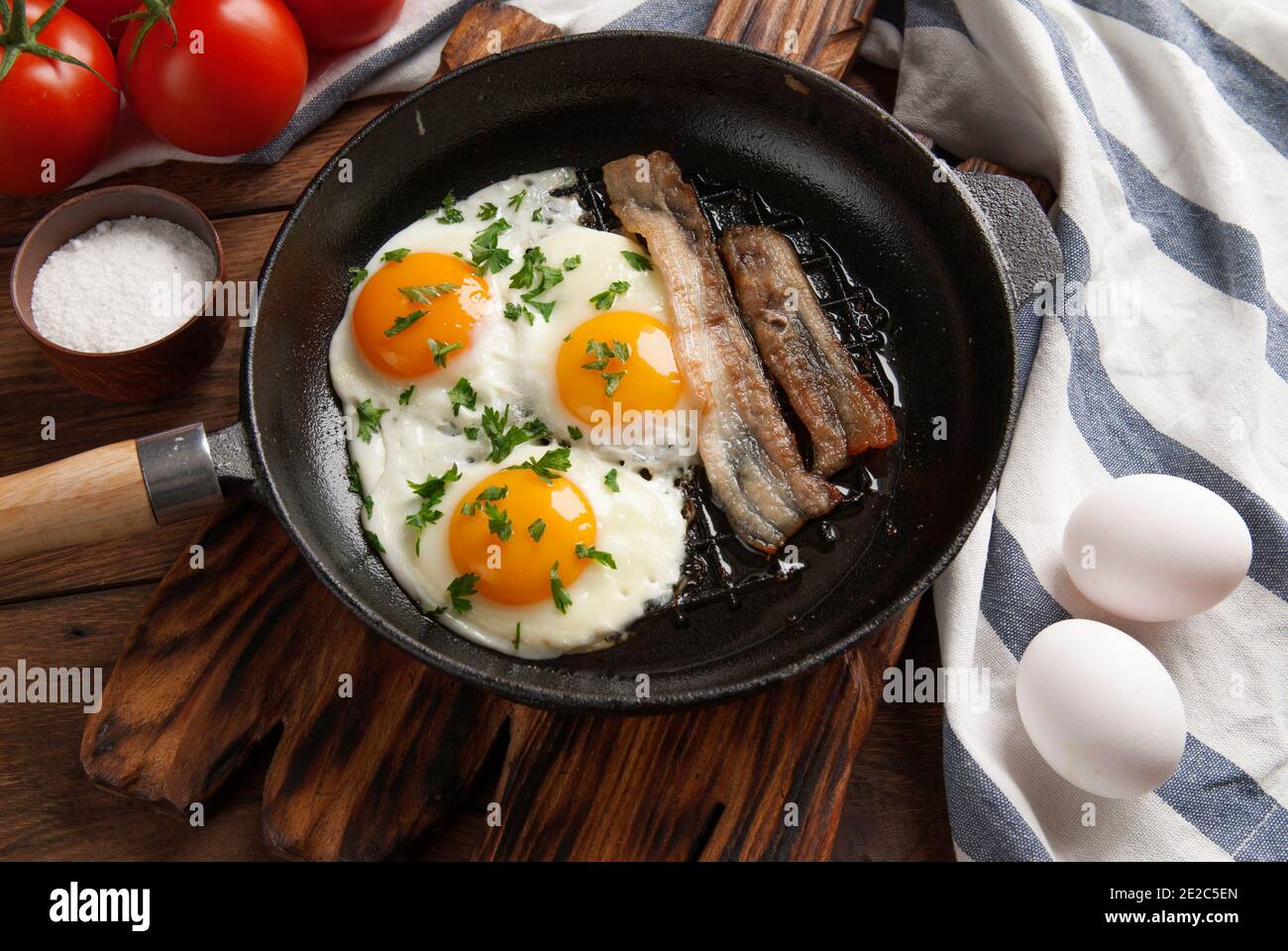 Scrambled eggs and bacon in a small pan on the kitchen table Stock Photo
