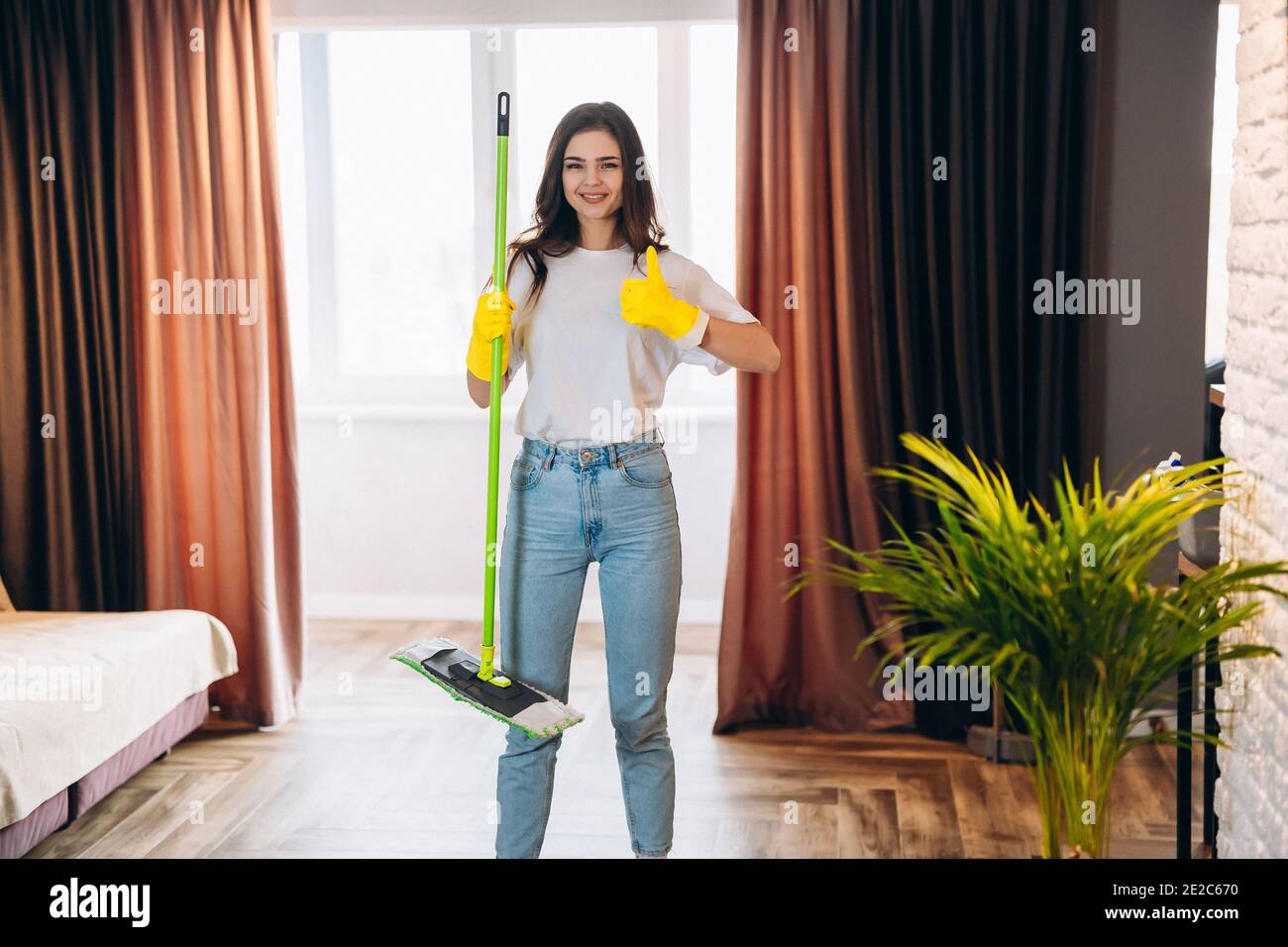 Full length photo of positive cheerful housewife wearing yellow rubber  gloves, enjoy washing floor hold mop feel content wearing denim jeans  casual cl Stock Photo - Alamy