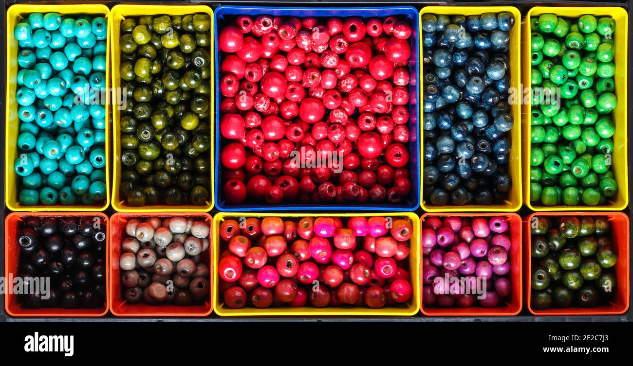 colourfull wooden beads sorted in compartments by colour in plastic box organiser Stock Photo