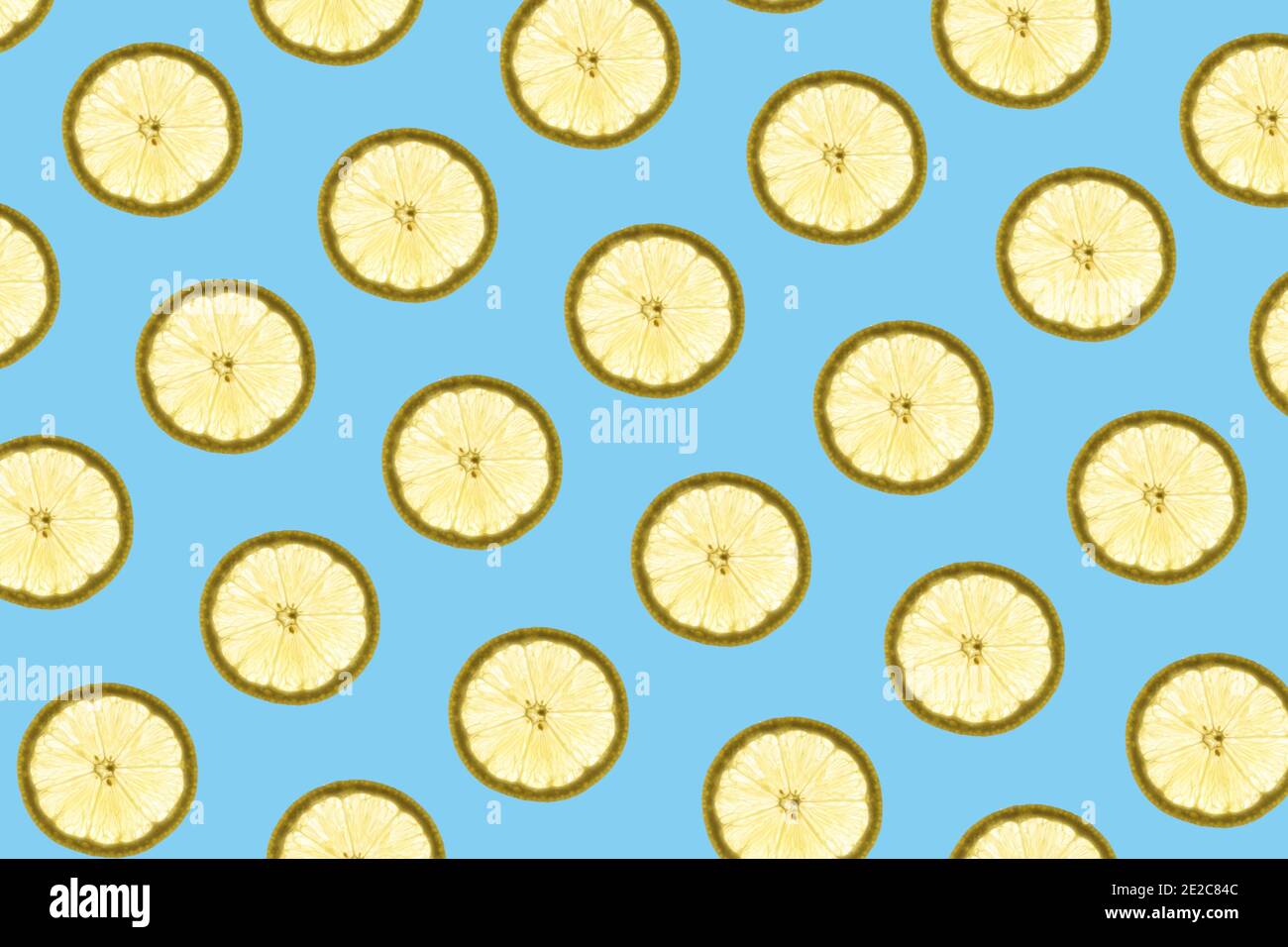 Pattern made of backlit lemon slices on blue background Stock Photo