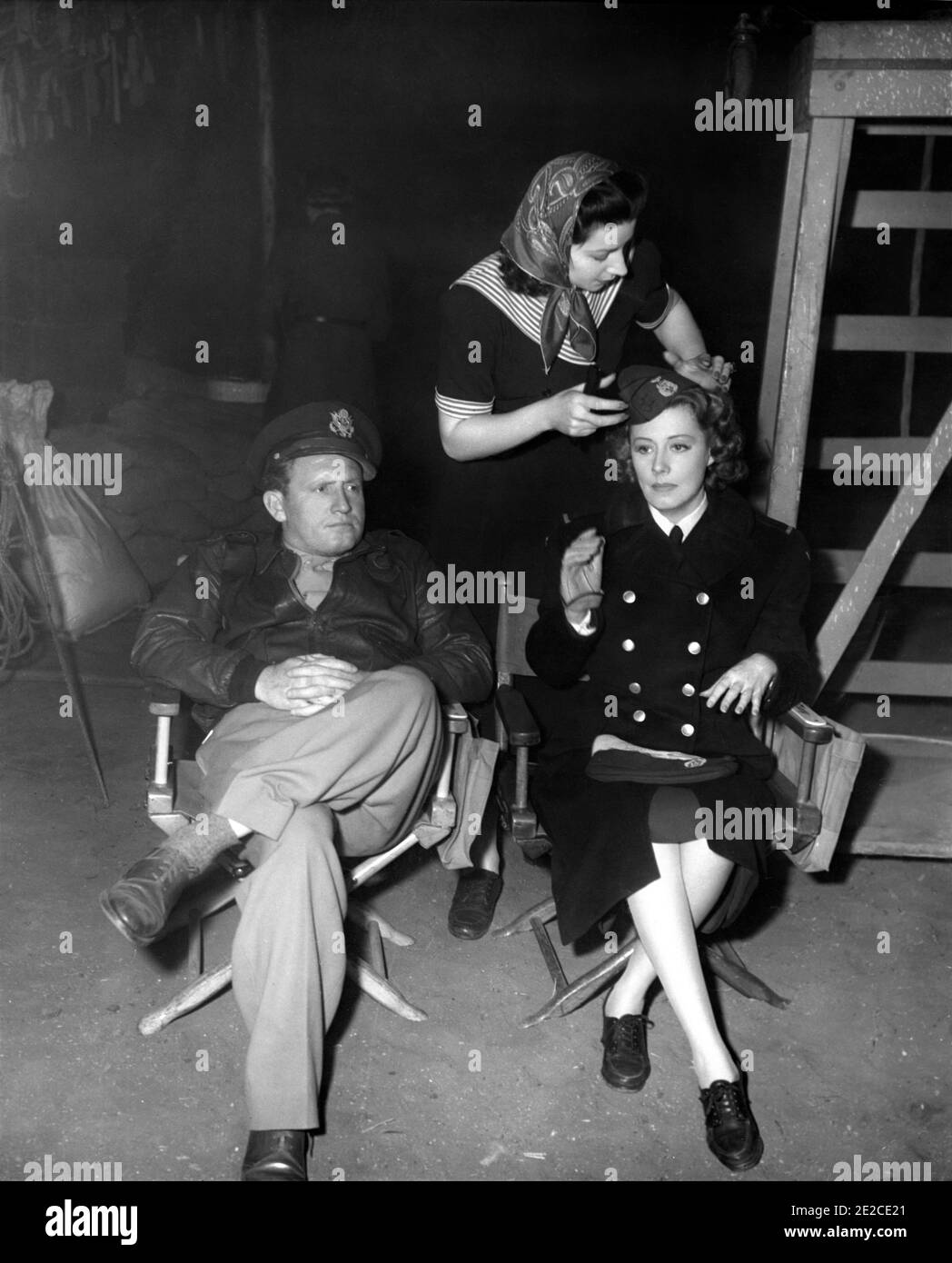 SPENCER TRACY and IRENE DUNNE on set candid while Wardrobe Assistant places her Cap on correctly during filming of A GUY NAMED JOE 1943 director VICTOR FLEMING screenplay Dalton Trumbo Metro Goldwyn Mayer Stock Photo