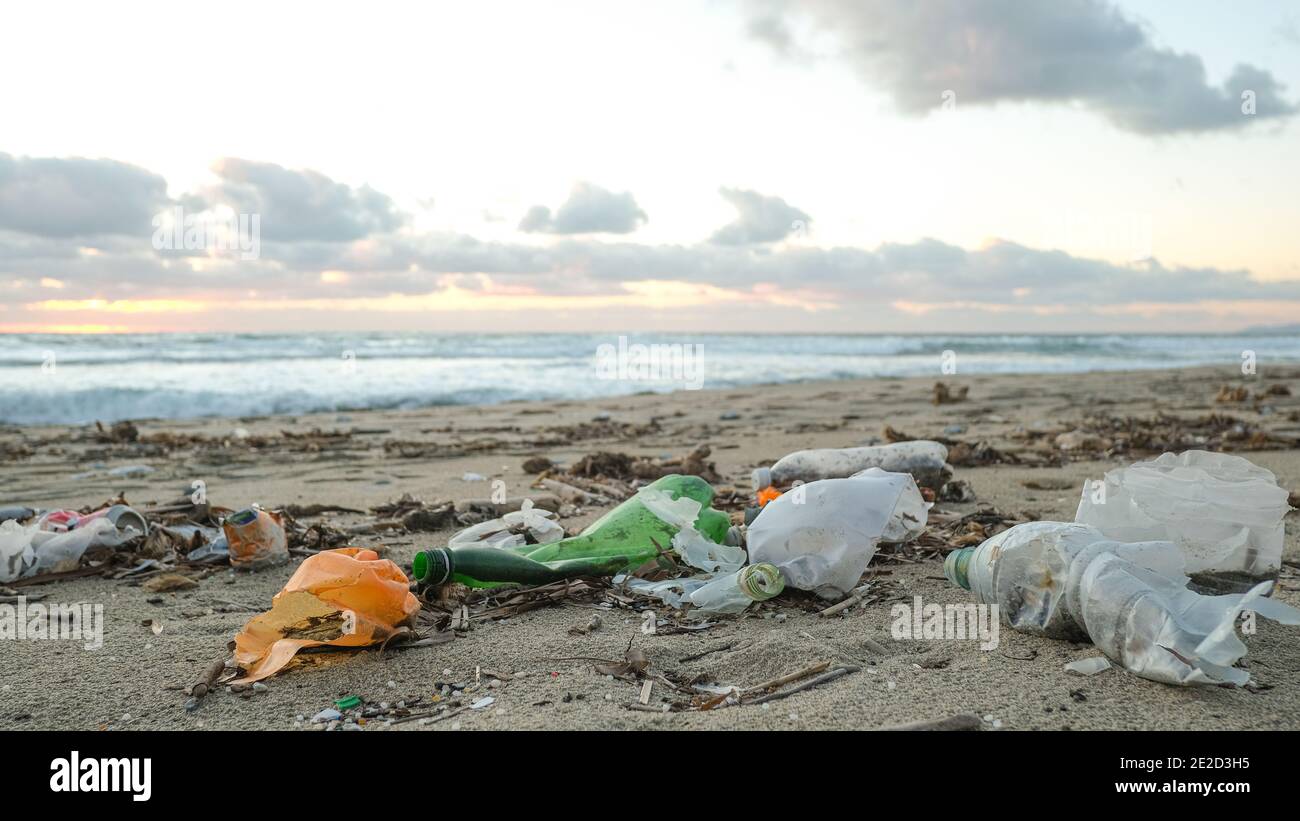 Plastic bottles trash pollution on contaminated ocean sea coast,sunset time,environmental waste Stock Photo