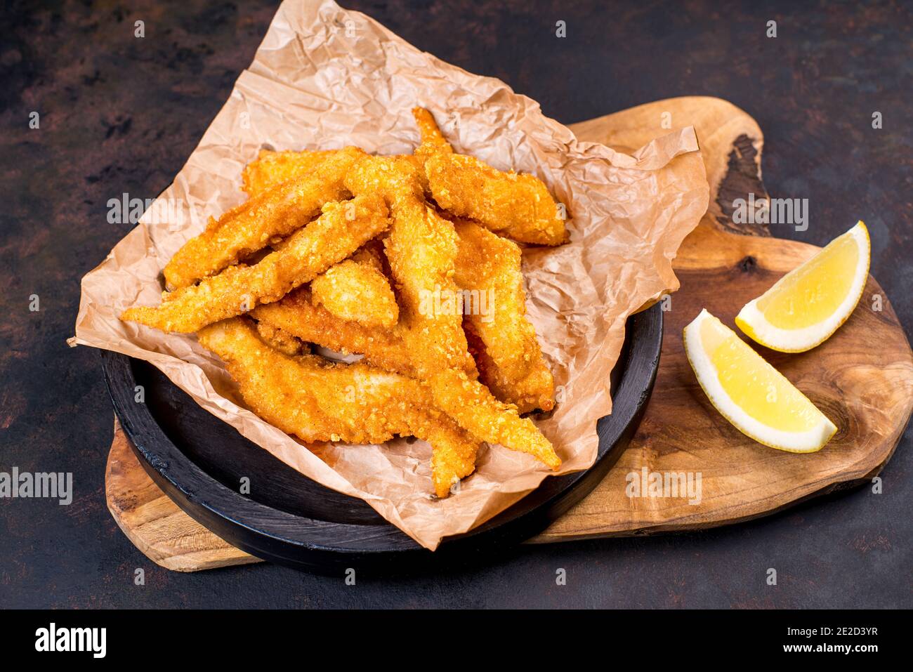 Fried chicken dippers in black bucket with sauce on black background