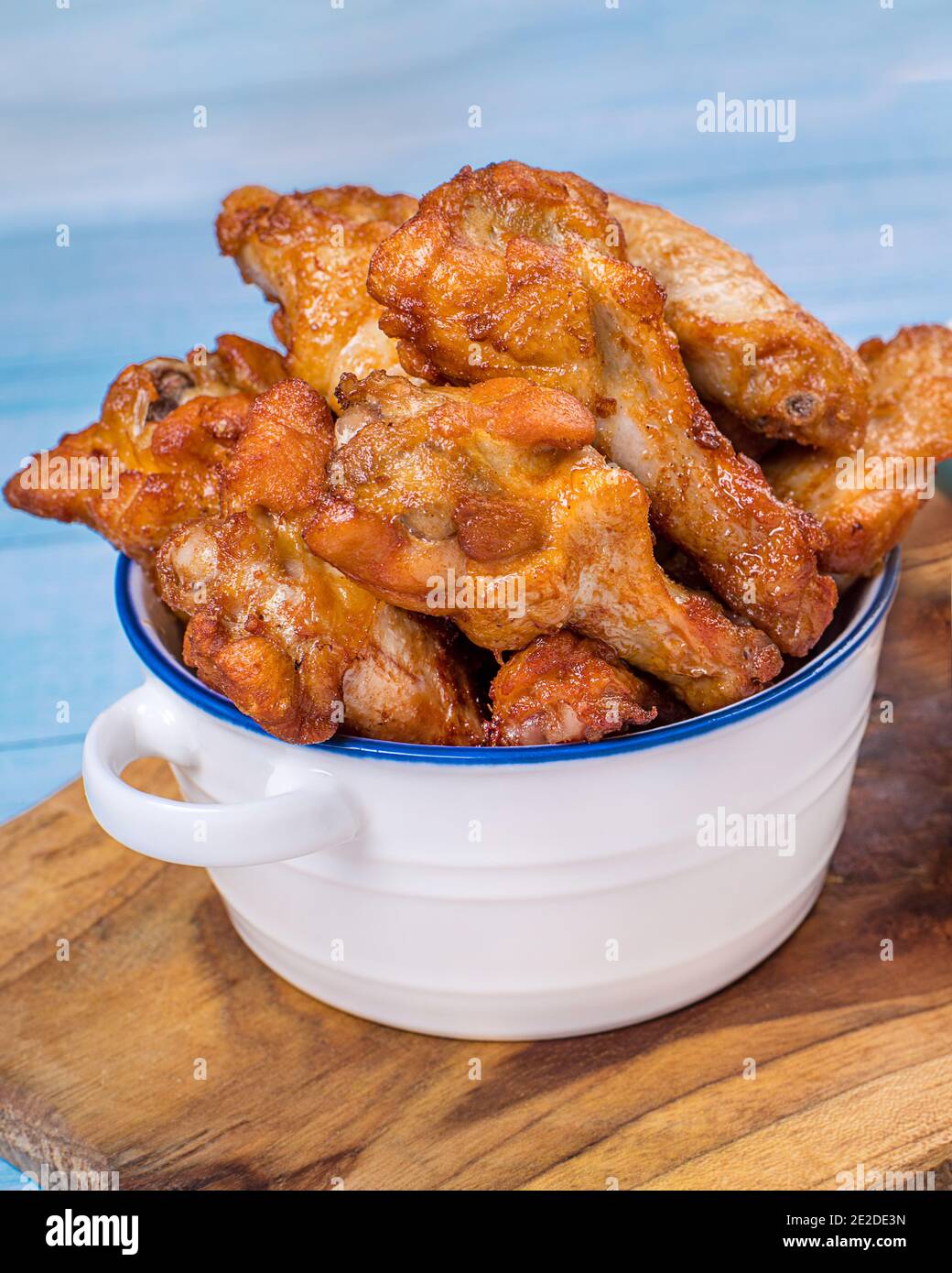 Fried chicken dippers in bucket with sauce on blue background.Chicken