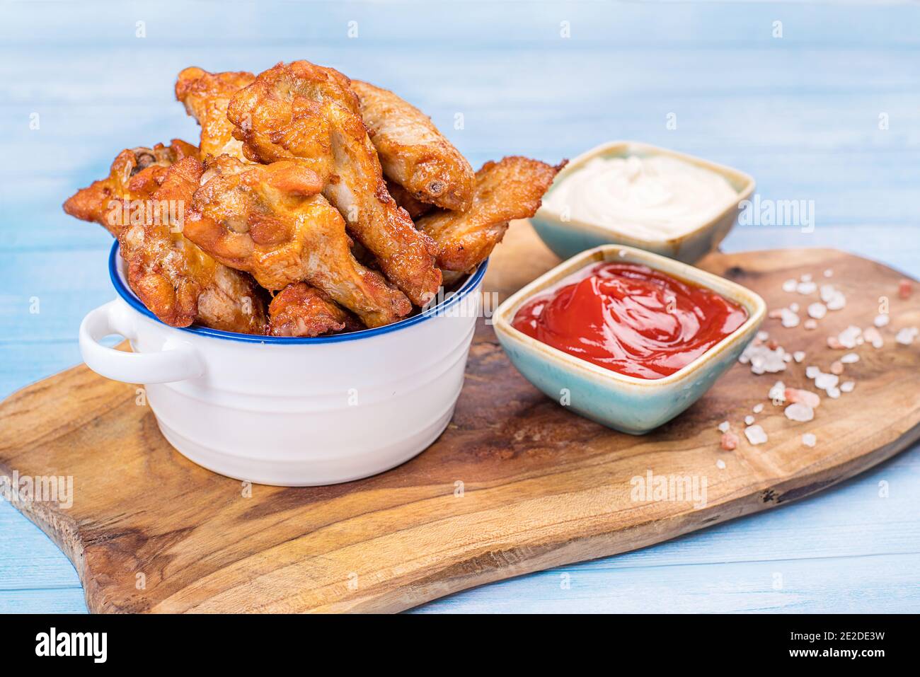 Fried chicken dippers in bucket with sauce on blue background.Chicken
