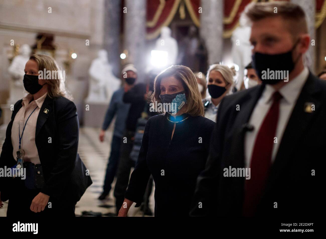 Washington, USA. 13th Jan, 2021. U.S. House Speaker Nancy Pelosi (C) wearing a protective mask walks through the hallways in Capitol Building in Washington, DC, the United States, Jan. 13, 2021. A majority of lawmakers in the U.S. House on Wednesday voted for impeaching President Donald Trump over 'incitement of insurrection,' making him the first president to be impeached twice. Credit: Ting Shen/Xinhua/Alamy Live News Stock Photo