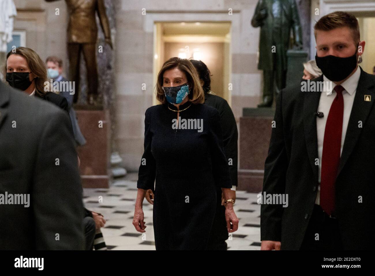 Washington, USA. 13th Jan, 2021. U.S. House Speaker Nancy Pelosi (C) wearing a protective mask walks through the hallways in Capitol Building in Washington, DC, the United States, Jan. 13, 2021. A majority of lawmakers in the U.S. House on Wednesday voted for impeaching President Donald Trump over 'incitement of insurrection,' making him the first president to be impeached twice. Credit: Ting Shen/Xinhua/Alamy Live News Stock Photo
