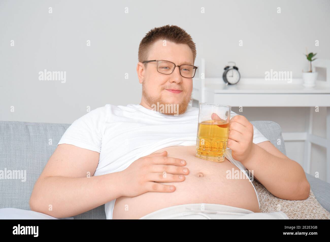 Overweight man drinking beer at home. Weight loss concept Stock Photo