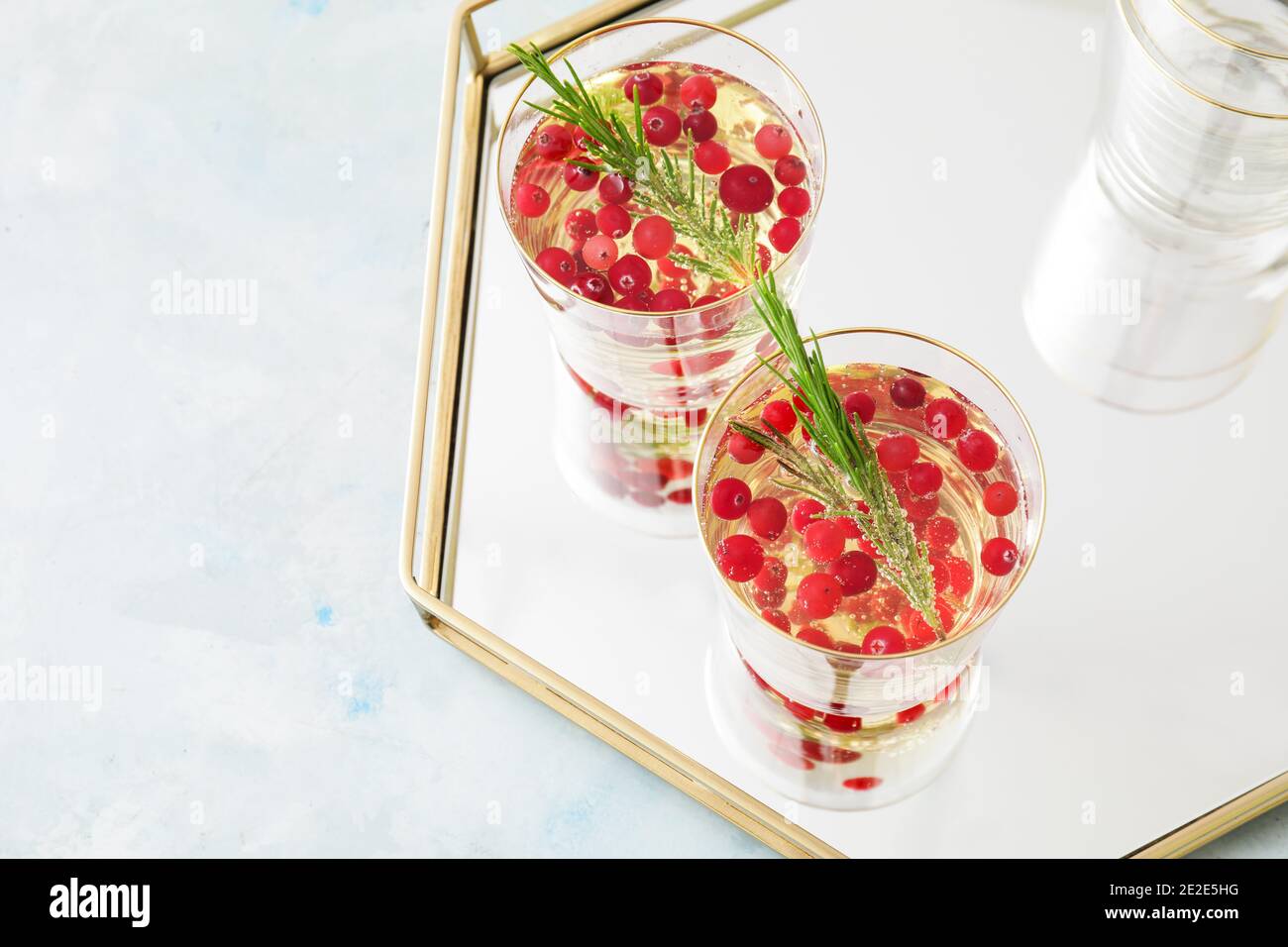 Glasses of champagne cocktail with cranberry and rosemary on tray Stock Photo
