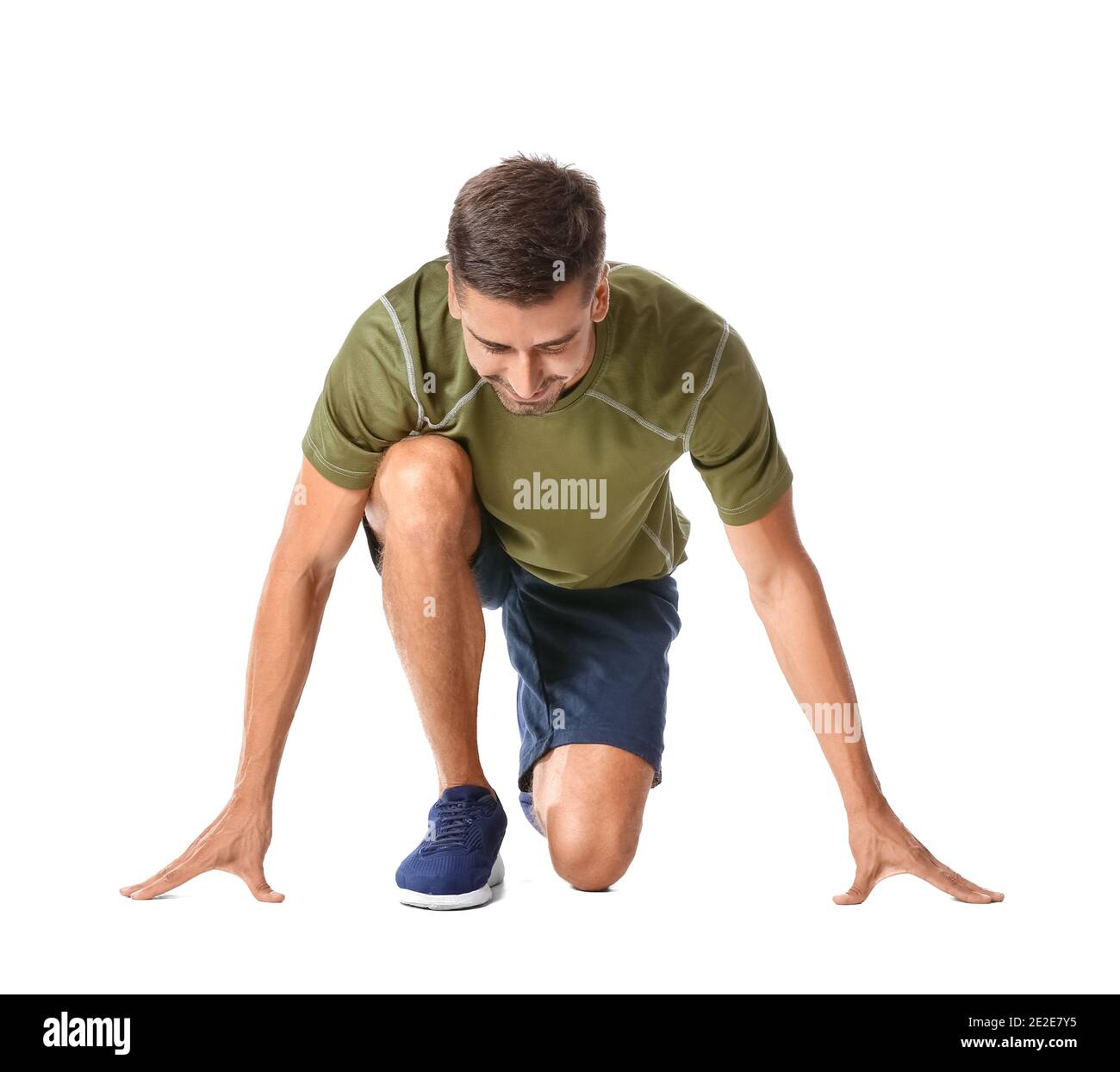Sporty young man standing in crouch start position isolated on white