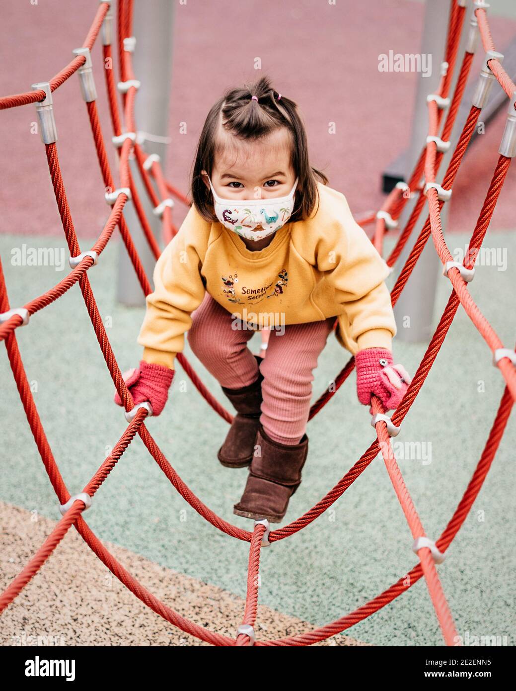 Toddler playing at the playground wearing a mask Stock Photo