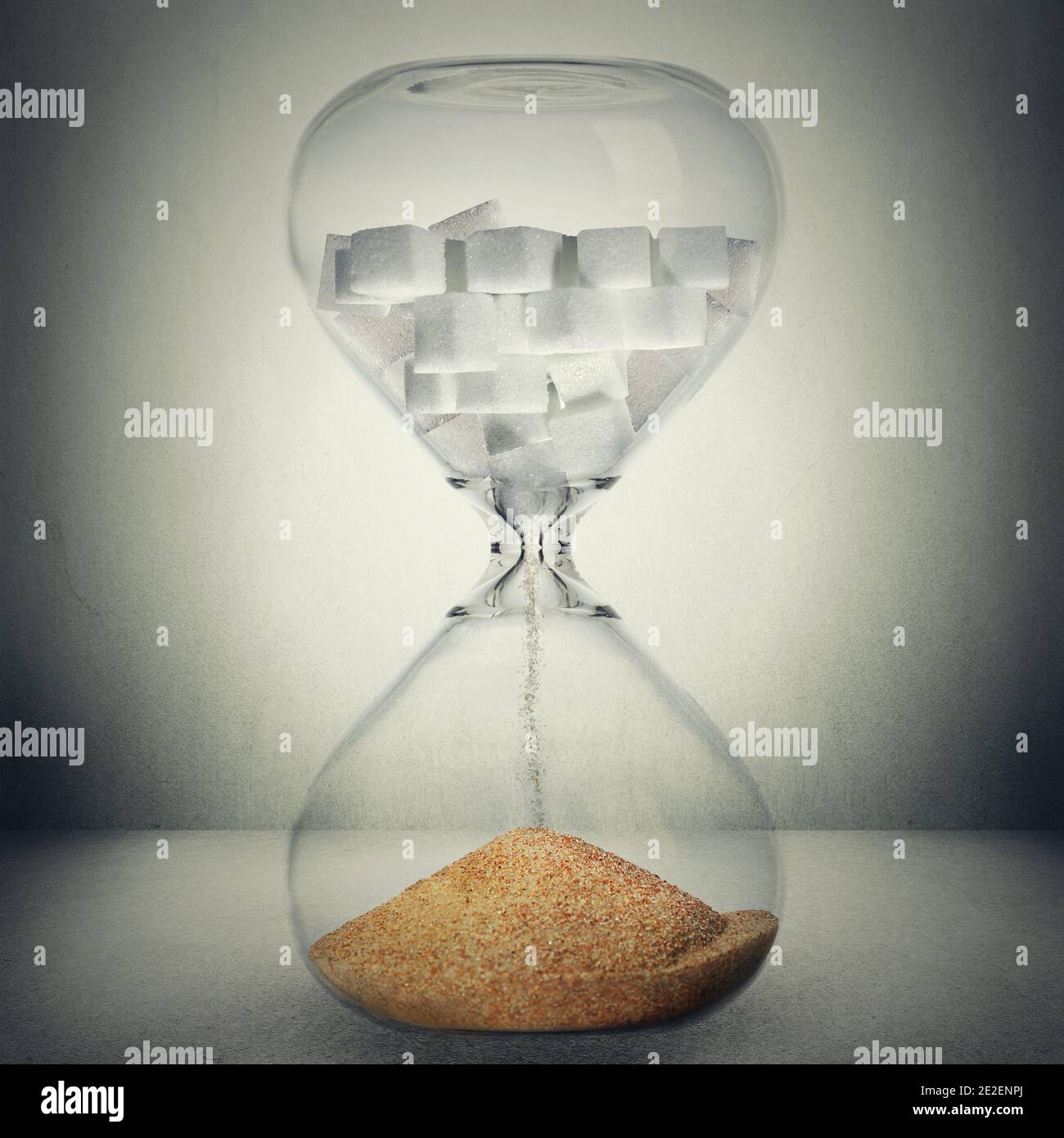 Sugar kills in time, death concept. Closeup of hourglass with sugar in cubes that is pouring down transforms in sand or gold, meaning making sugar is Stock Photo