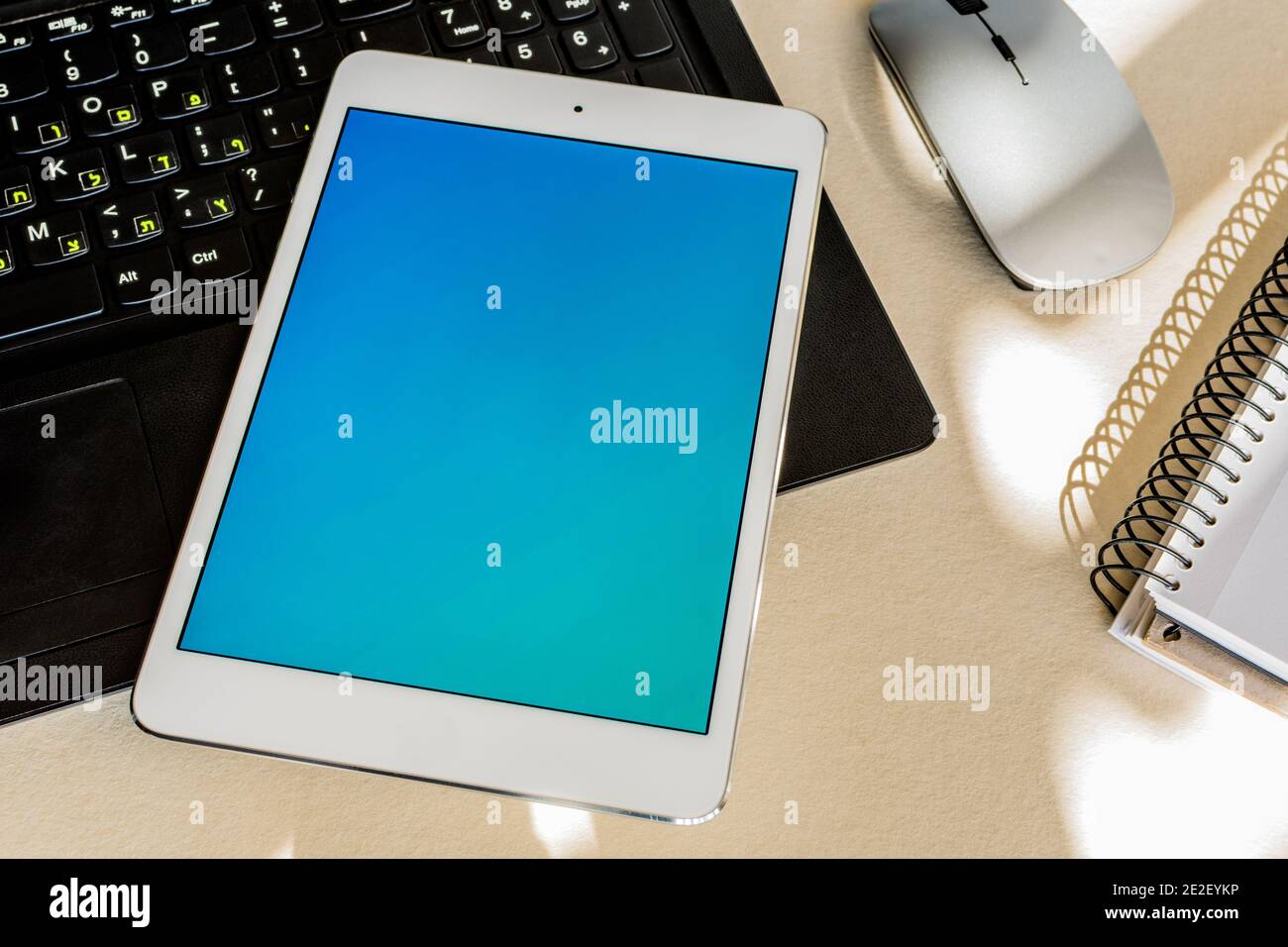 Tablet with blue screen on the keyboard of a laptop on a desk - technology and business concept Stock Photo