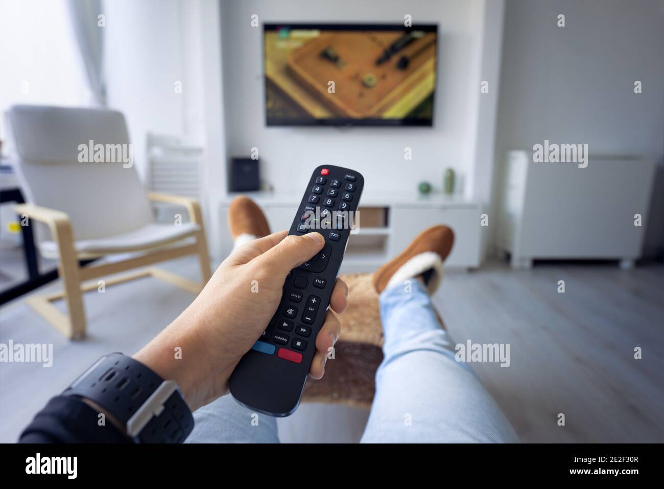 Man watching TV at home. Holding remote controller and switching channel.  First person view Stock Photo - Alamy