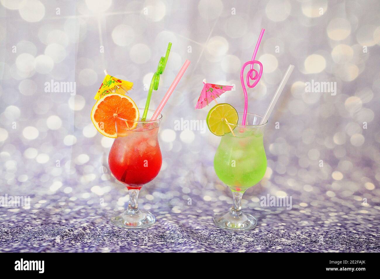 Two glasses with bright fruit drinks and slices of citrus lime and grapefruit on a gray shiny background. Close-up. Stock Photo