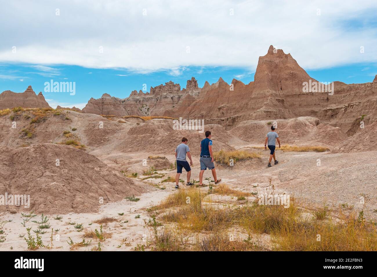 Unrecognizable young men hiking between the rock formations of Badlands national park, South Dakota, USA (United States of America). Stock Photo