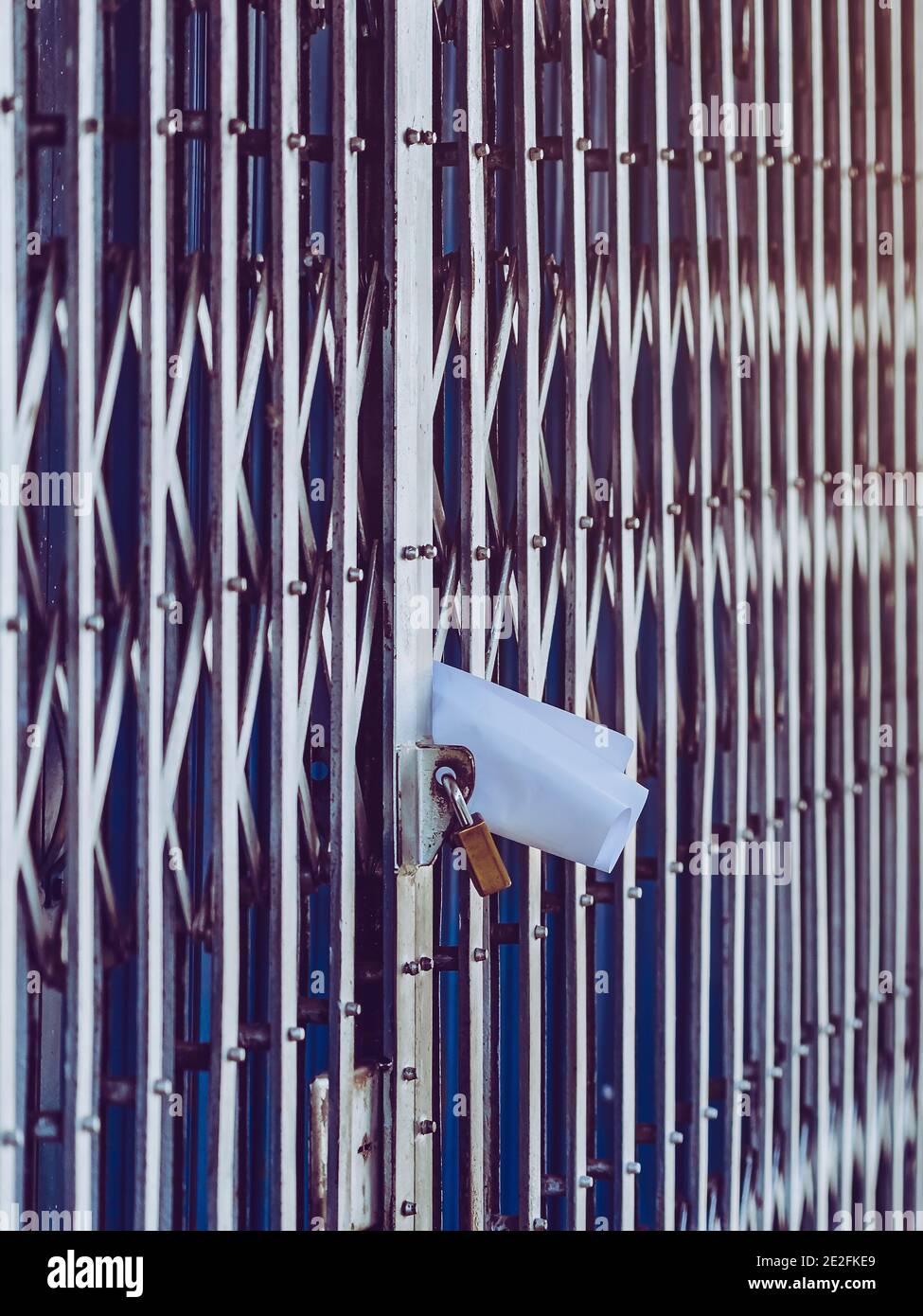 White paper notification attached to closed retractable folding metallic  gate.Metal collapsible sliding grille door normally use at shop houses in  Asi Stock Photo - Alamy