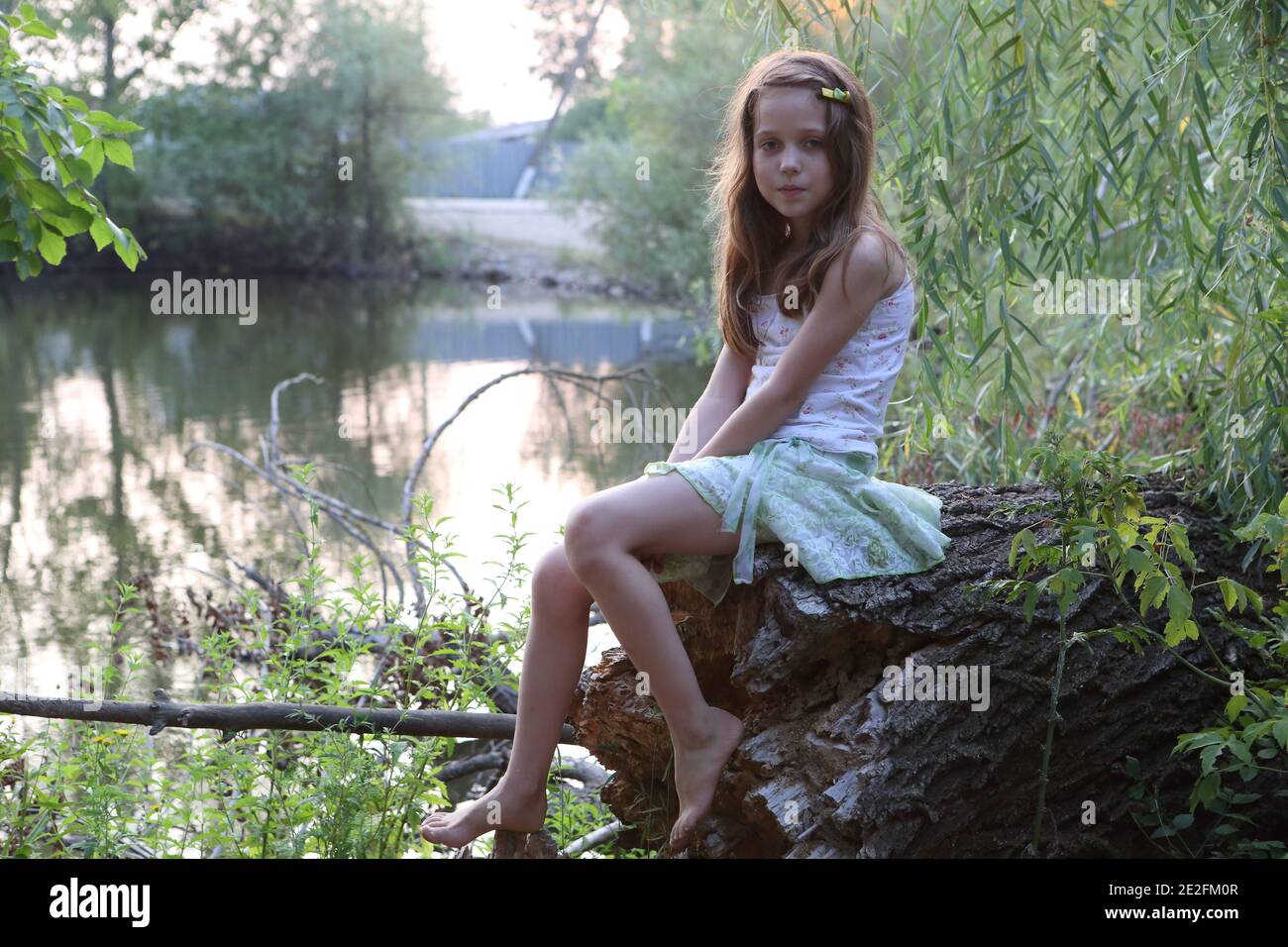 Girl sitting on the river bank Stock Photo - Alamy