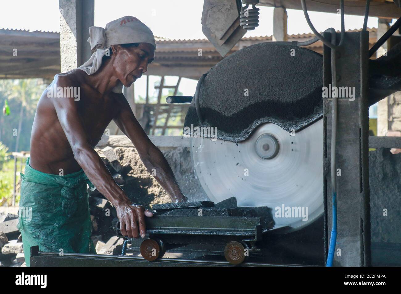 A man cuts a black volcanic stone with a water jet cutting machine, Bali, Indonesia Stock Photo