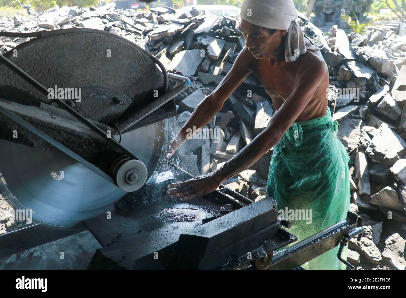 A man cuts a black volcanic stone with a water jet cutting machine, Bali, Indonesia Stock Photo