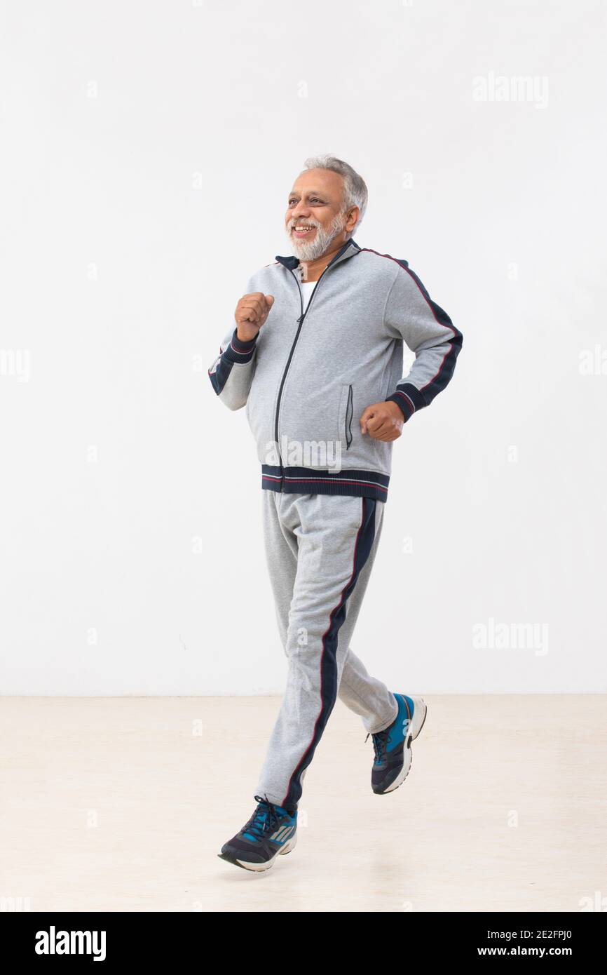 AN OLD MAN HAPPILY RUNNING IN TRACKSUIT Stock Photo