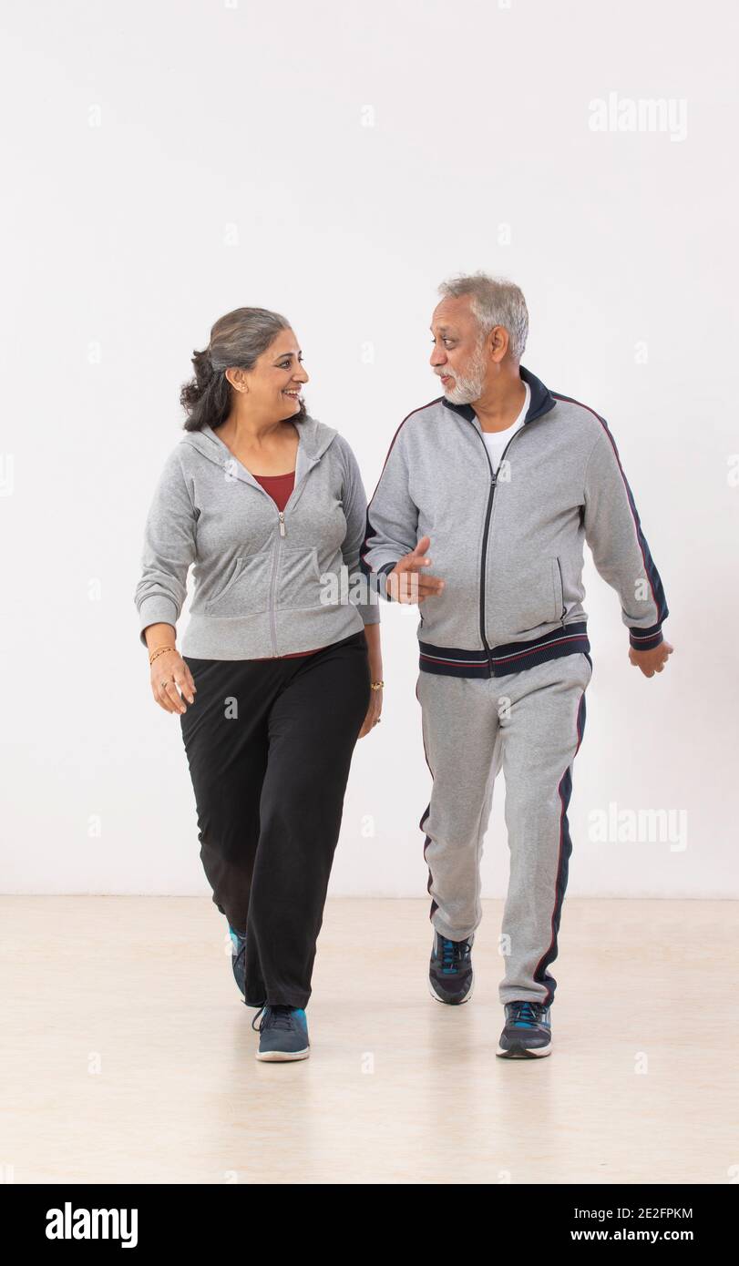 AN OLD MAN HAPPILY TALKING TO HIS WIFE WALKING TOGETHER Stock Photo