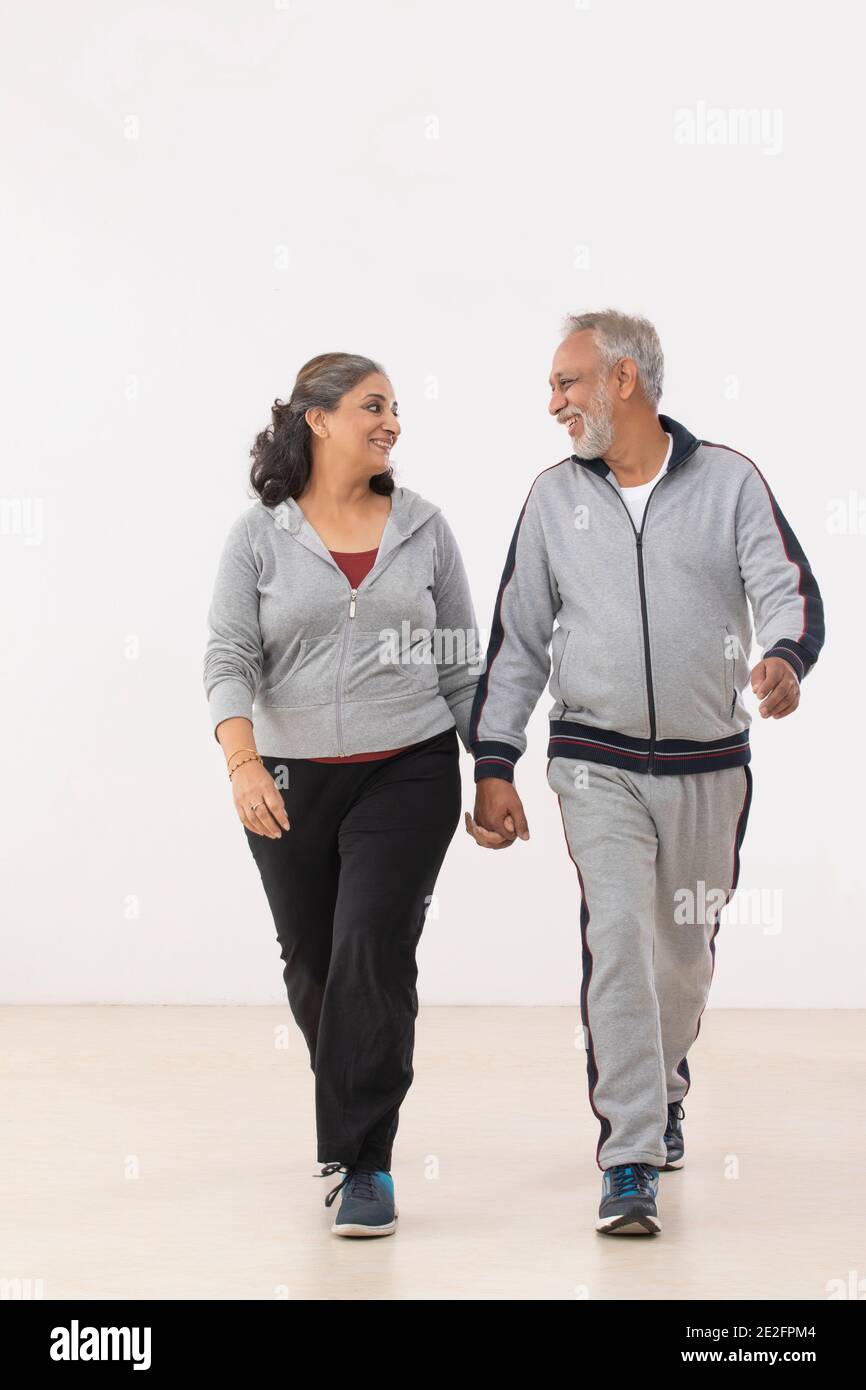 A HAPPY COUPLE WALKING TOGETHER WHILE HOLDING HANDS Stock Photo