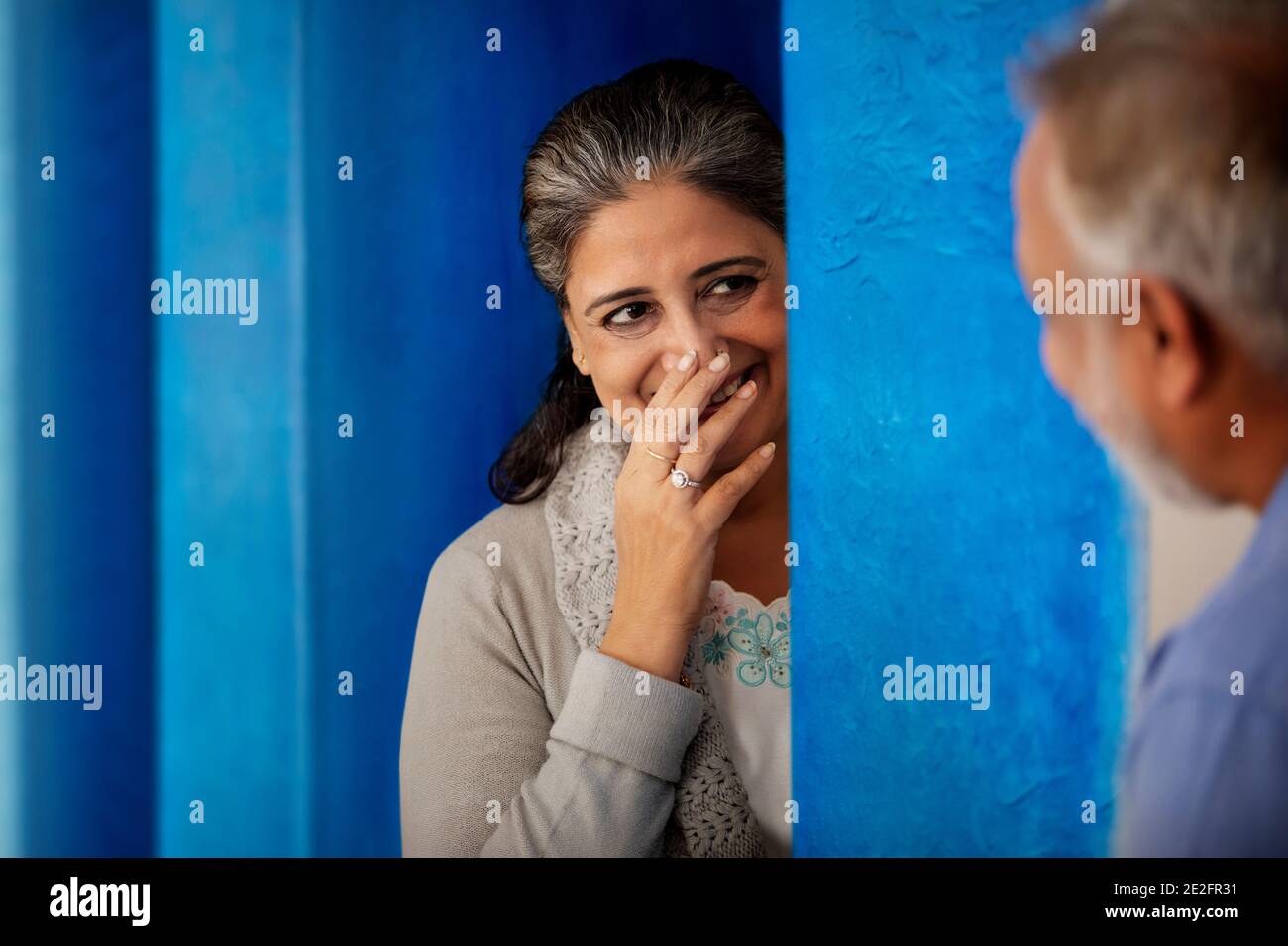 A SENIOR ADULT WOMAN LAUGHING WITH HUSBAND STANDING IN FRONT Stock Photo