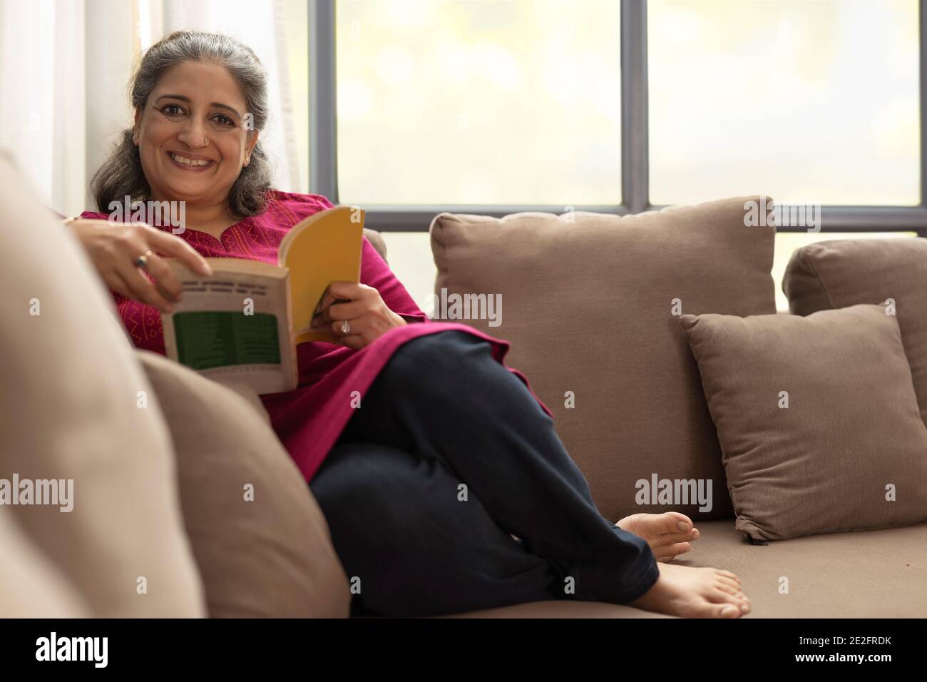 A SENIOR ADULT WOMAN HAPPILY SITTING AND READING BOOK Stock Photo - Alamy