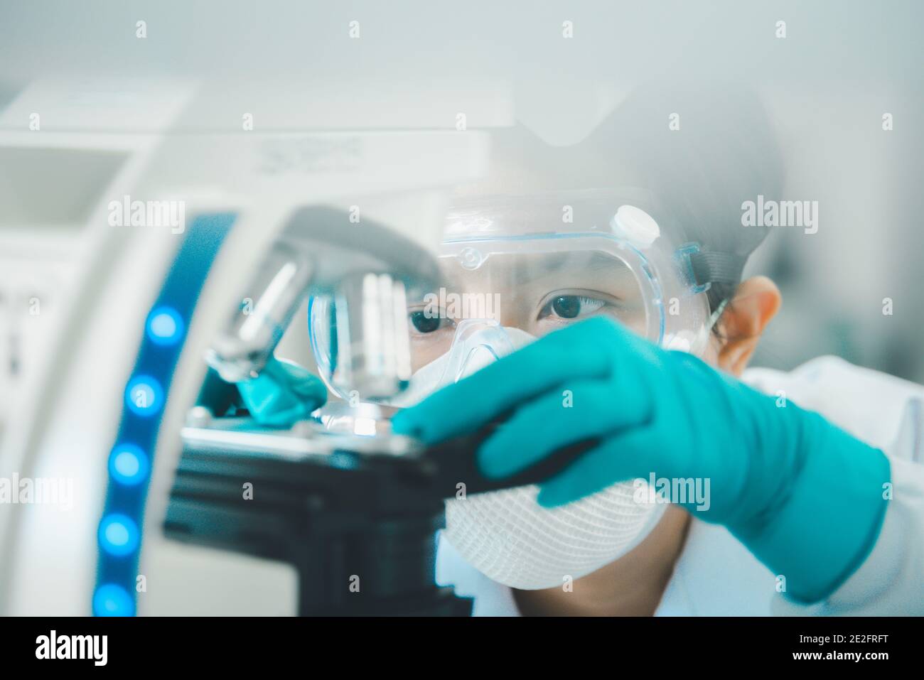 Doctor or scientist looking through a microscope in medical research lab or science laboratory. Stock Photo