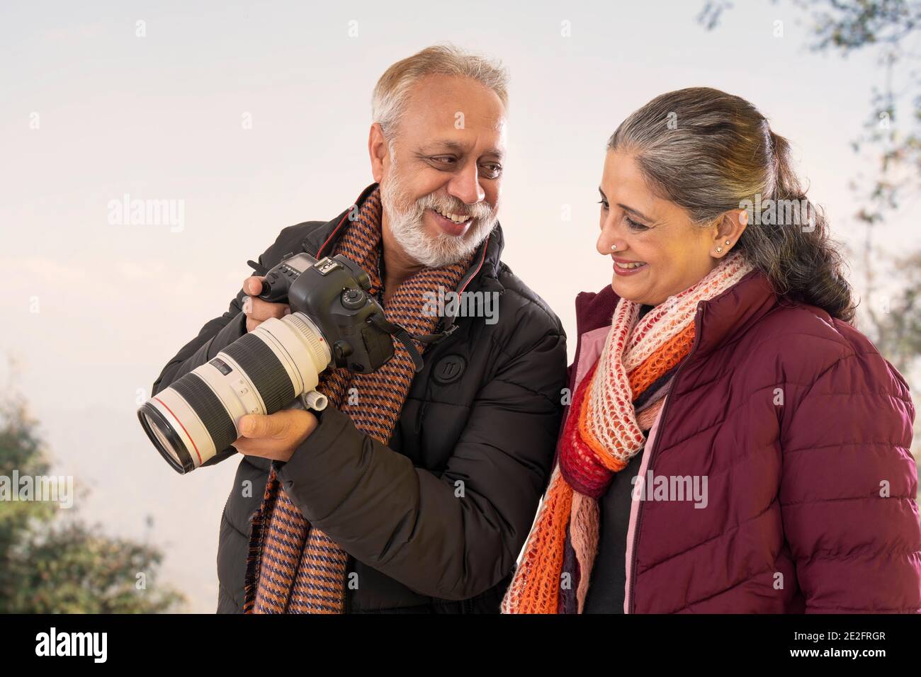 A SENIOR ADULT MAN SHOWING PICTURES ON CAMERA TO WIFE Stock Photo