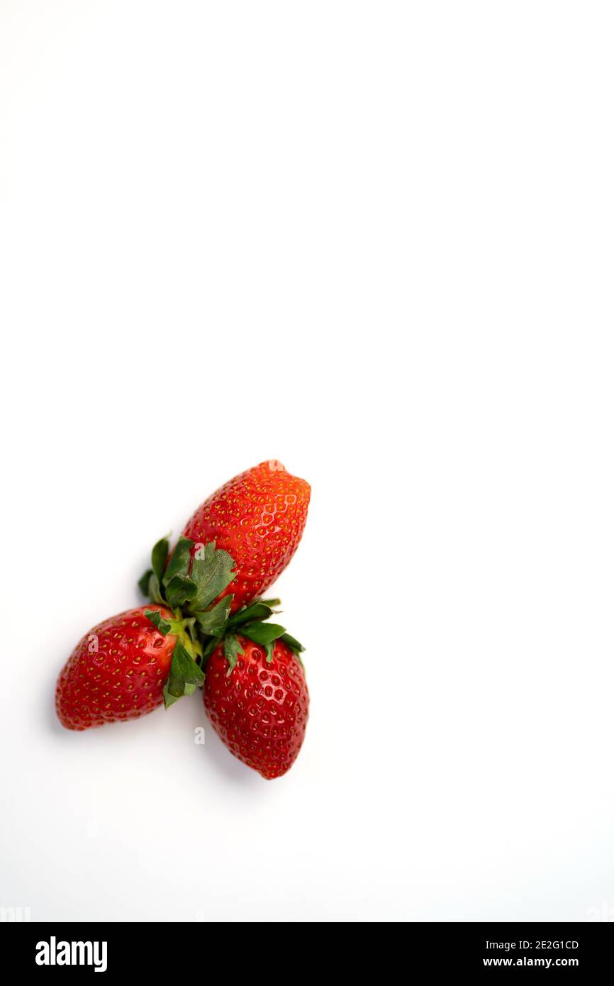 Three ripe fresh red strawberries with green leaves isolated on a white ...