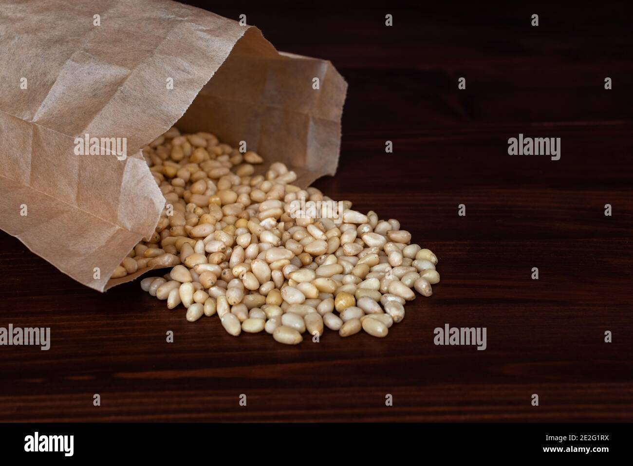 Bag of pine nuts on wooden table. Scattered nuts. Healthy snack concept Stock Photo