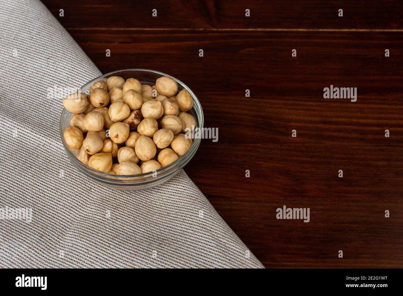 Roasted hazel nuts in a bowl on rustic background. Scattered nuts Stock Photo