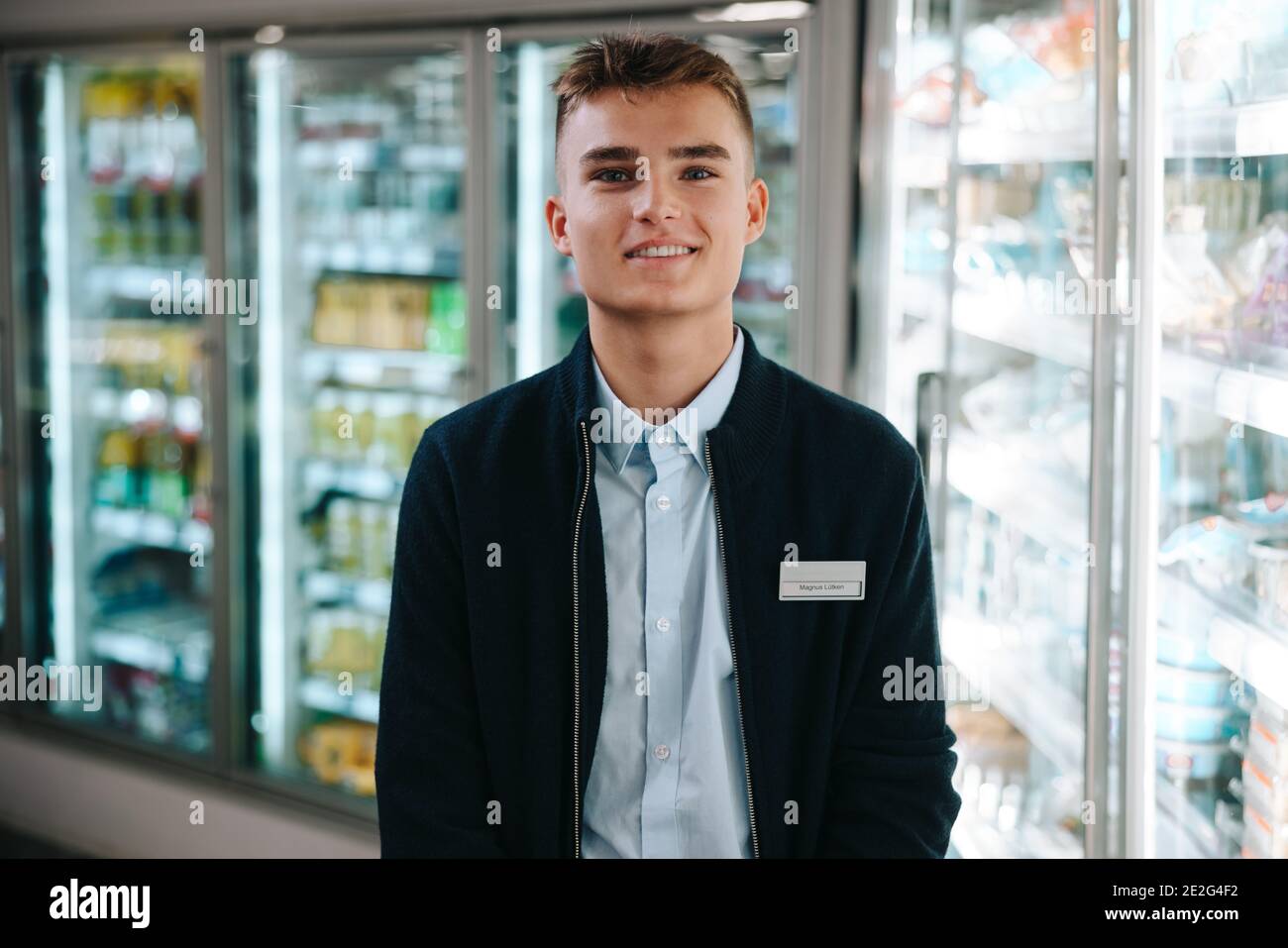 Supermarket trainee employee. Young male worker on holiday job at grocery shop. Stock Photo