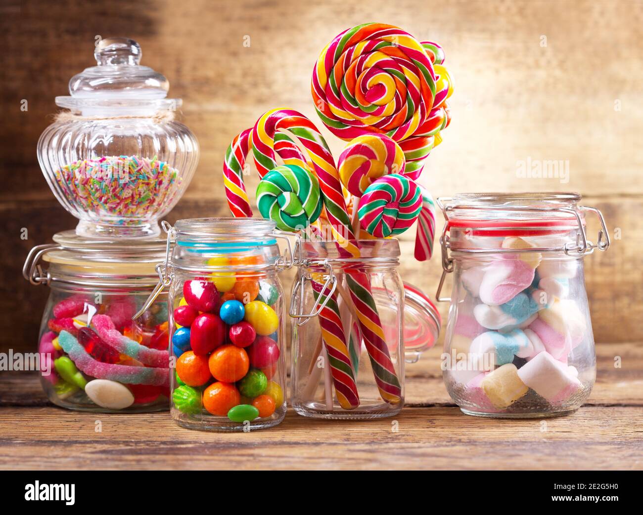 Colorful candies, lollipops and marshmallows in a glass jars on wooden