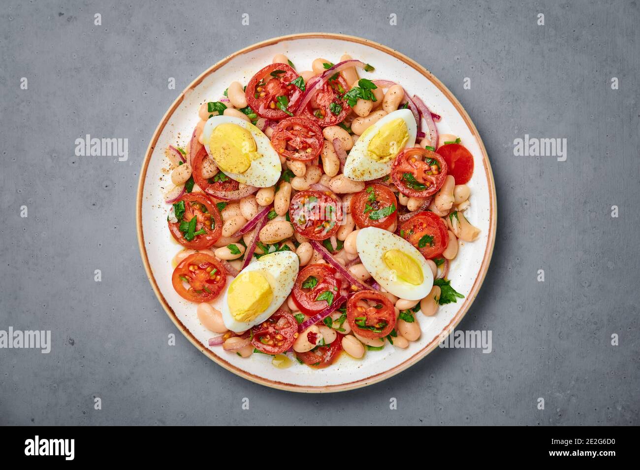 A Piyaz salad on white plate on gray concrete table top. Turkish cuisine vegetarian dish. Middle eastern cuisine food. Top view Stock Photo