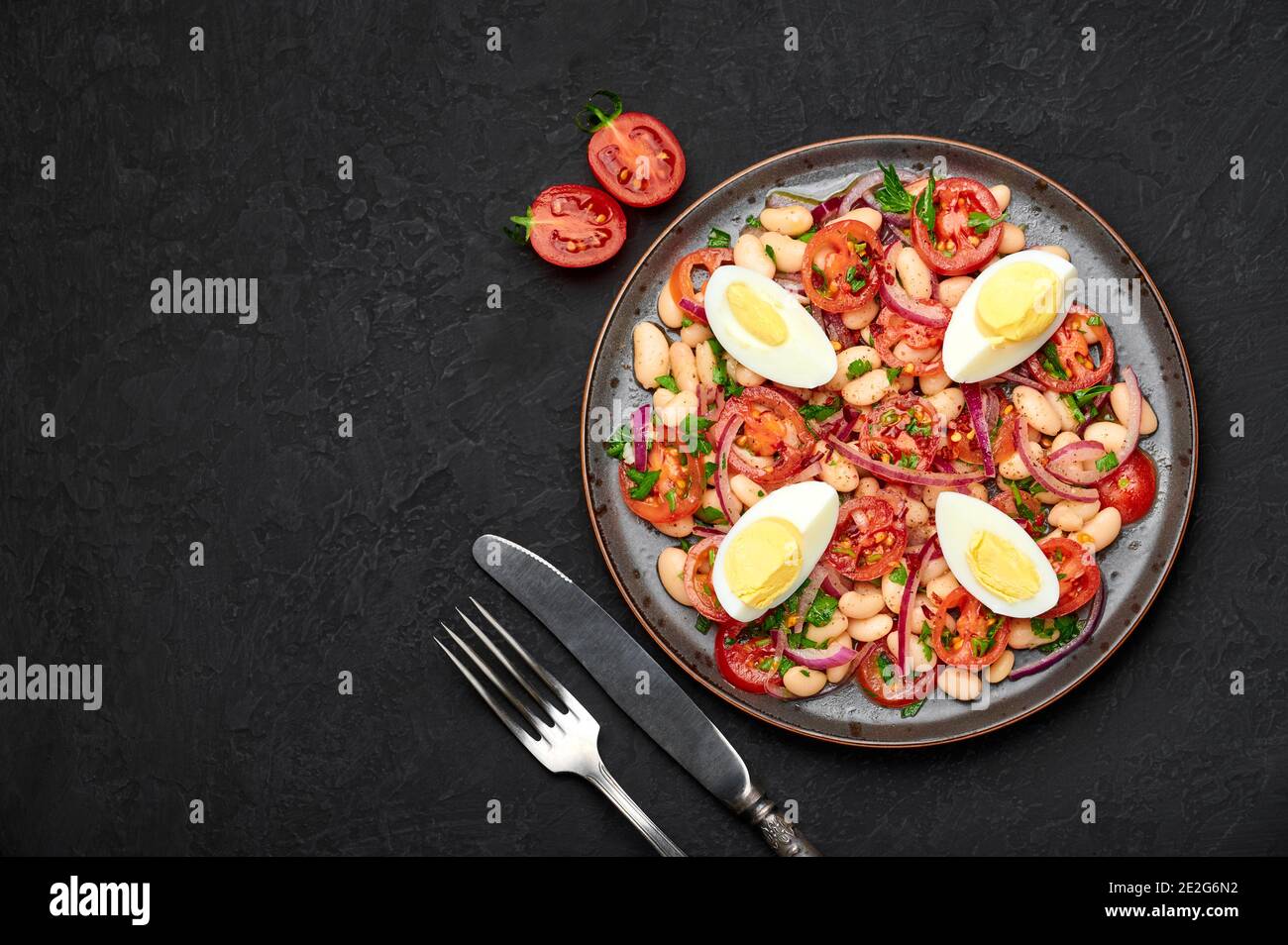 A Piyaz salad on black plate on dark slate table top. Turkish cuisine vegetarian dish. Middle eastern cuisine food. Top view. Copy space Stock Photo
