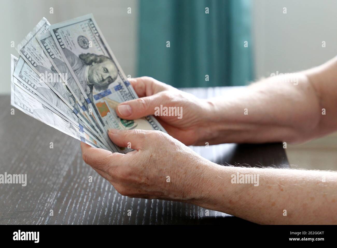 Elderly woman with US dollars in wrinkled hands close up. Concept of pension payments, savings at retirement, pensioner with money Stock Photo